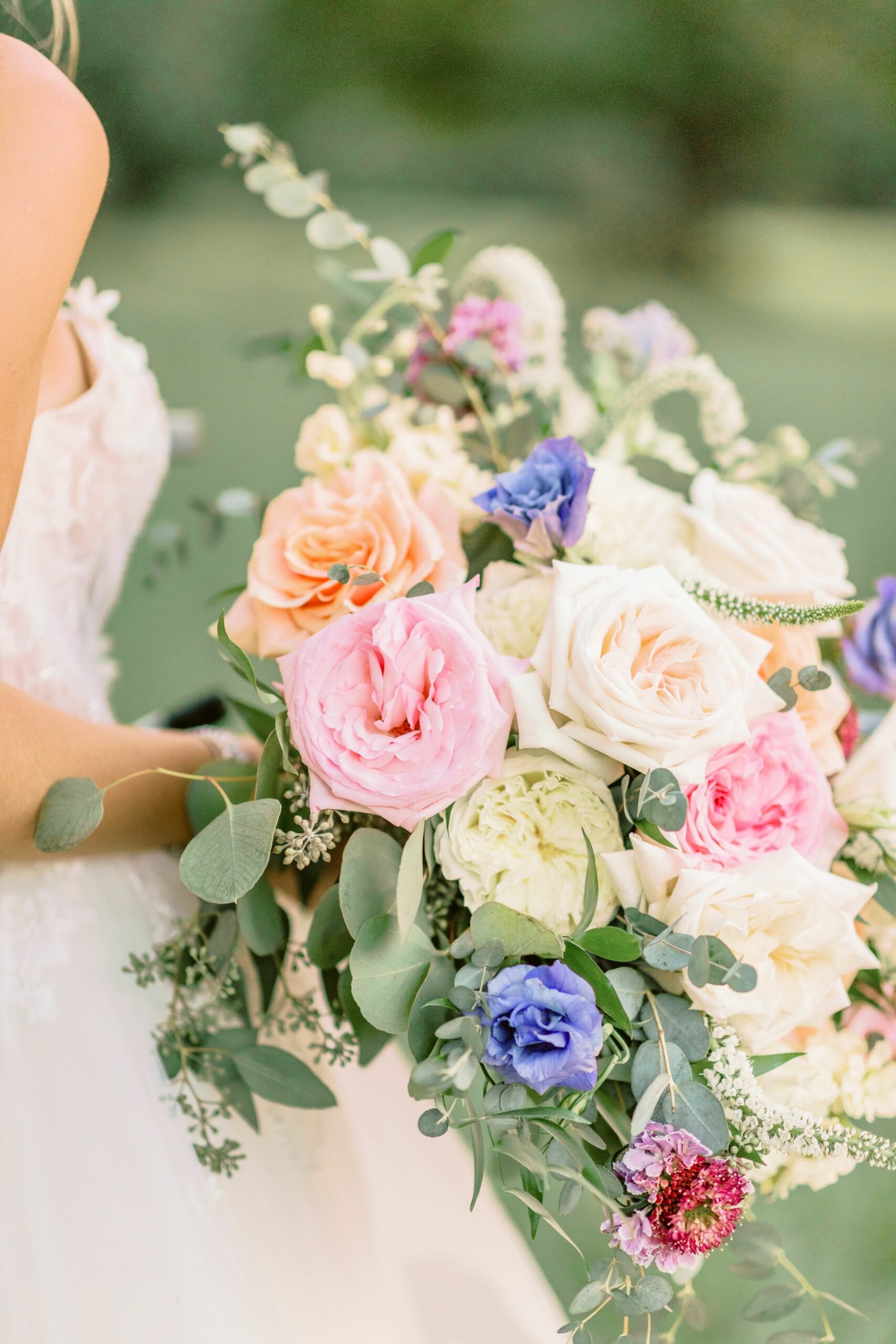 Vertical shot of a bride holding a beautiful flower bouquet isolated on a blurred background